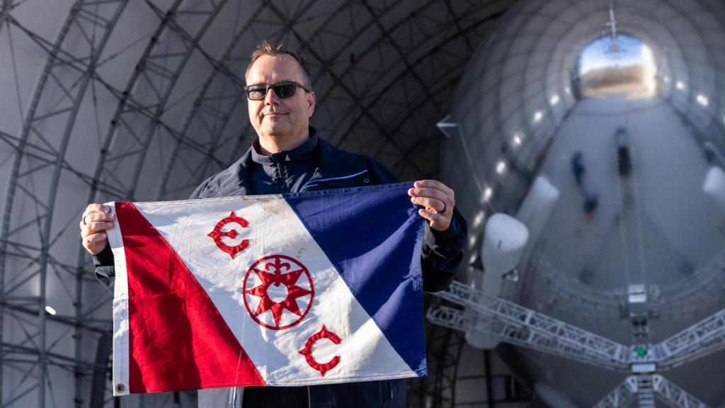 Mikkel Verstegaard, CEO de Sceye, en uno de los hangares de la compañía; en la mano, sostiene una bandera del Explorer's Club, al que pertenece.