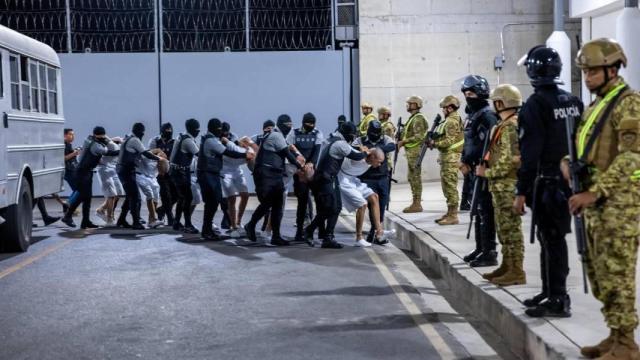Fotografía cedida por el gobierno de El Salvador donde se observan a agentes del Centro del Confinamiento del Terrorismo (CECOT), trasladando a un grupo de detenidos provenientes de Estados Unidos, este lunes en Tecoluca (El Salvador).