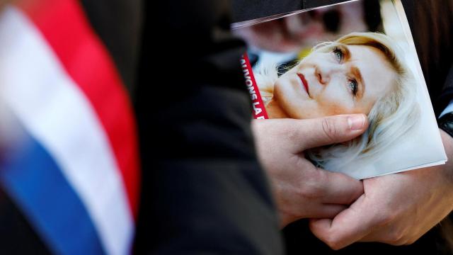 Un funcionario de Reagrupamiento Nacional distribuye folletos en apoyo de la líder de extrema derecha.