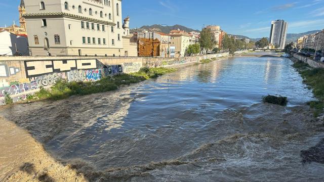 Imagen del río Guadalmedina con agua y, al fondo, las torres de Martiricos.