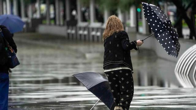 Una mujer intenta luchar contra la lluvia y el viento durante un temporal. (Archivo)