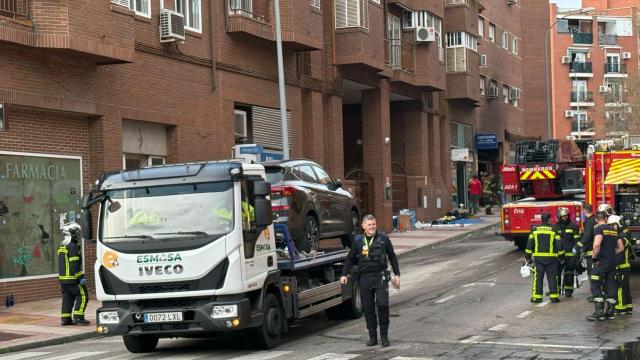 Una grua retirando un coche de la calle Lilos 6, donde se ha producido un incendio.