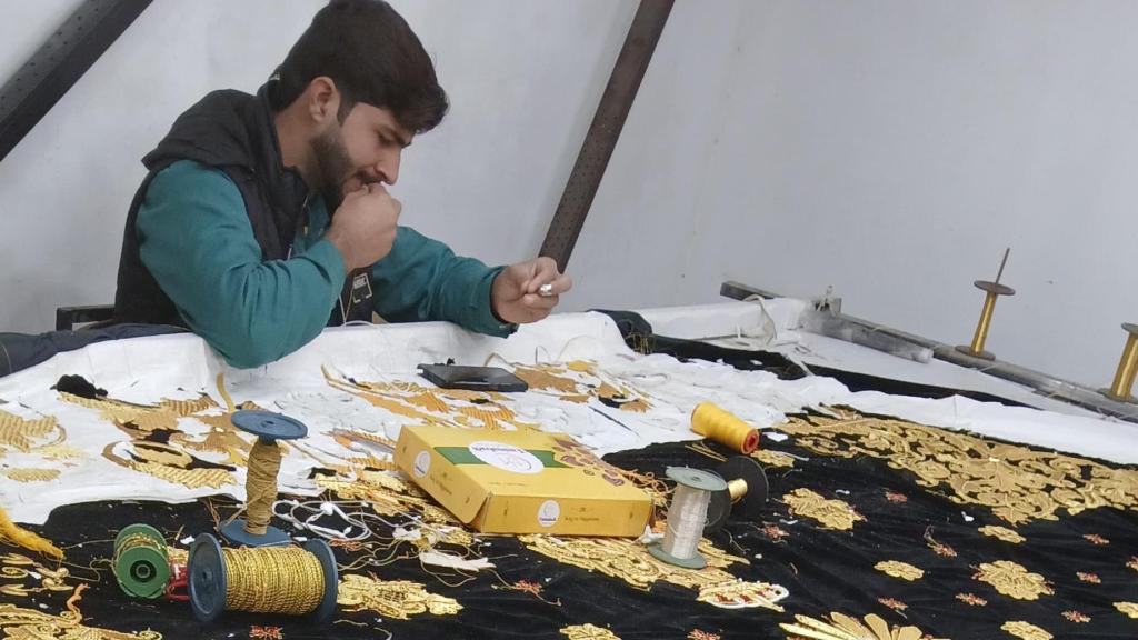 Uno de los trabajadores de Pakistán bordando el manto.