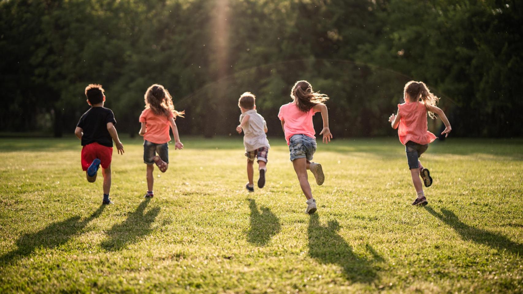 Un grupo de niños y niñas corriendo en el parque.