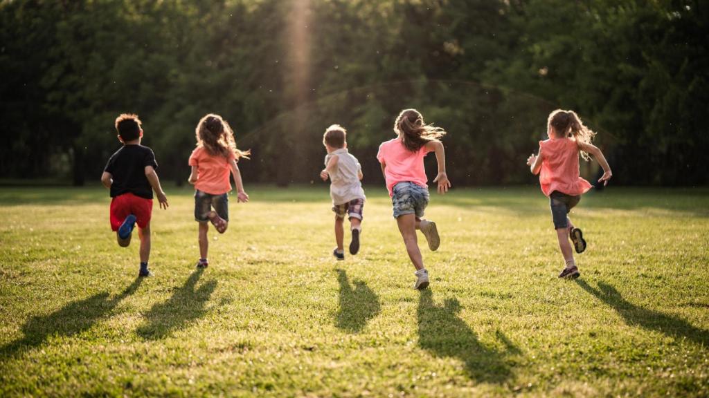 Un grupo de niños y niñas corriendo en el parque.
