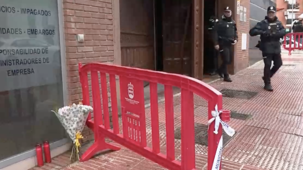 El portal de la calle Los Lilos 6 con flores y velas para recodar a Sergio y a Jesús.