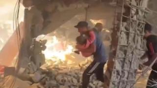 Un hombre saca entre los escombros el cuerpo de una niña tras el ataque de Israel a una escuela en Gaza.