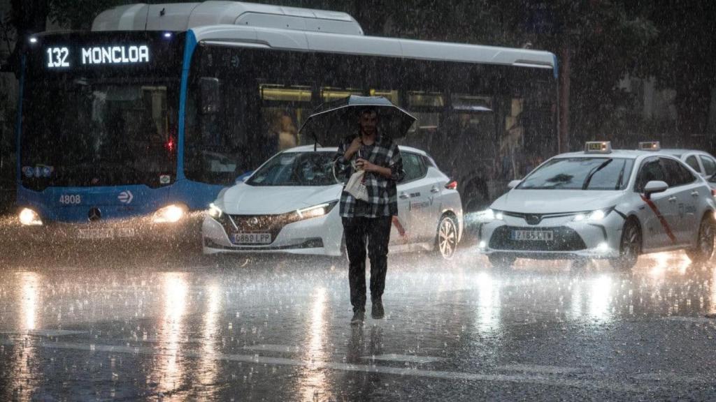 Una persona se resguarda de la lluvia en Madrid.