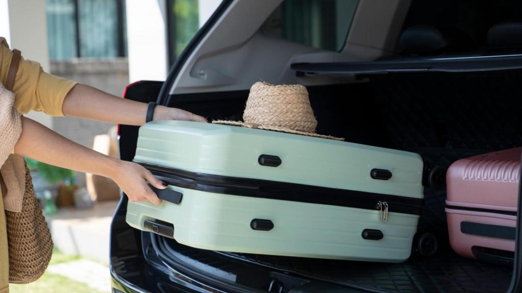 Una mujer guarda una maleta en el coche