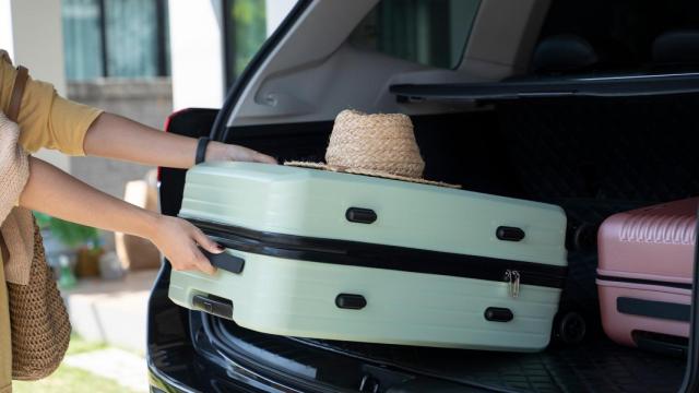 Una mujer guarda una maleta en el coche