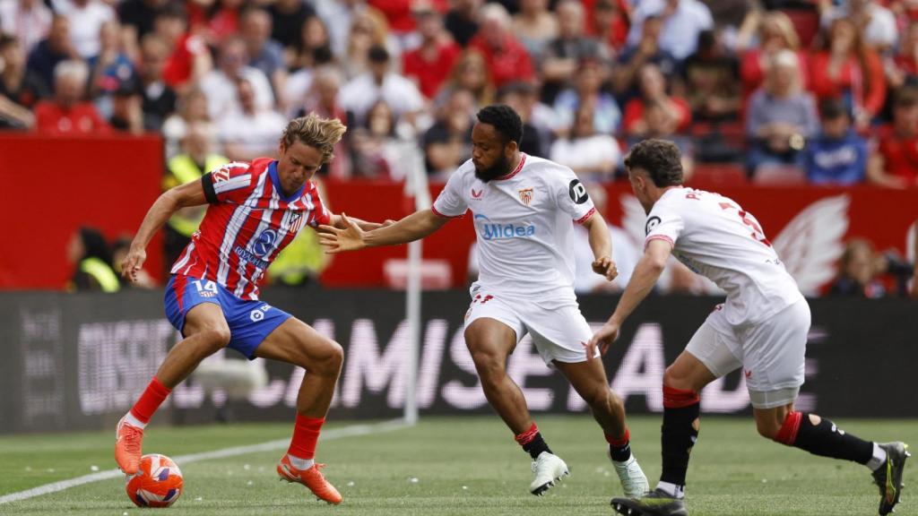 Marcos Llorente presionado por dos jugadores del Sevilla en el partido.