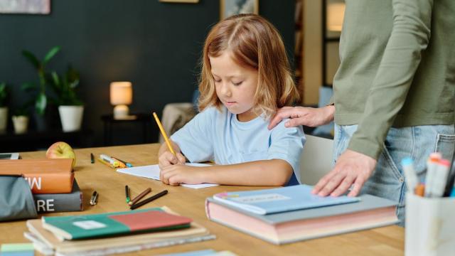 Una niña concentrada haciendo sus deberes escolares en una mesa.