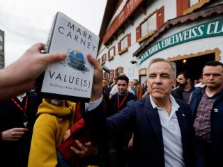 El primer ministro de Canadá, Mark Carney, coge un libro de un simpatizante para autografiarlo fuera del Victoria Edelweiss Club, durante su gira de campaña electoral del Partido Liberal en Victoria, Columbia Británica, Canadá 6 de abril de 2025.