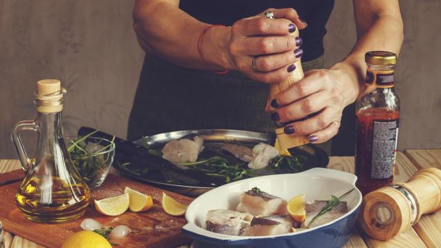 Imagen de archivo de un mujer sazonando pescado
