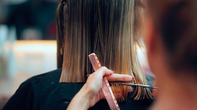Mujer cortándose el pelo.
