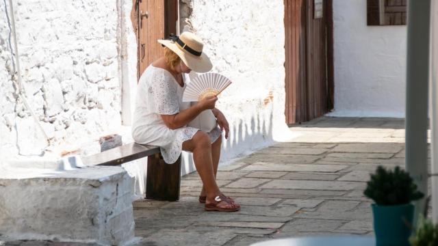 Una mujer a la sombra mientras se abanica