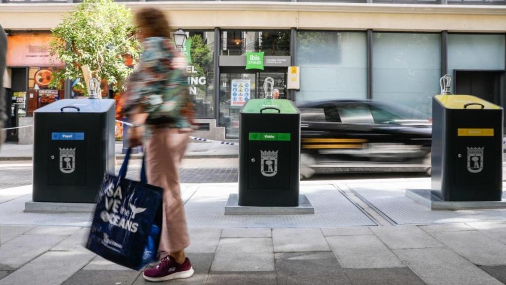 Imagen de archivo de una viandante pasando por delante de unos contenedores de recogida de residuos en una calle de Madrid.