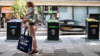 Imagen de archivo de una viandante pasando por delante de unos contenedores de recogida de residuos en una calle de Madrid.