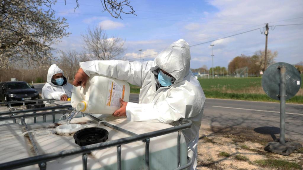 Un agente de las autoridades sanitarias llena un recipiente con líquido desinfectante durante una revisión a una granja por el brote de fiebre aftosa en Dunakiliti, Hungría.