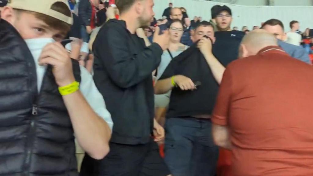 Algunos aficionados del Manchester United se tapan la cara.