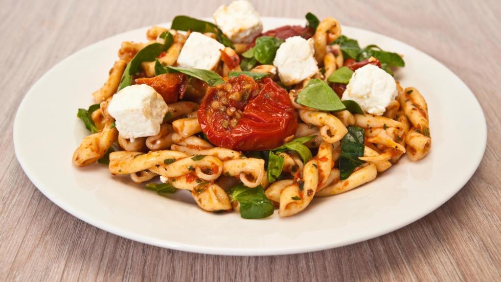 Un plato de pasta con queso feta y tomatitos cherry.