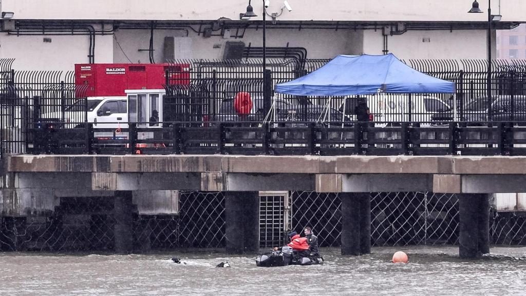 Buzos del Departamento de Policía de la Ciudad de Nueva York revisan las aguas donde un helicóptero turístico con una familia española abordo se estrelló este jueves en el río Hudson.