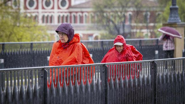 Peregrinos protegidos con chubasqueros a su paso por el Puente de Piedra este jueves en Logroño.
