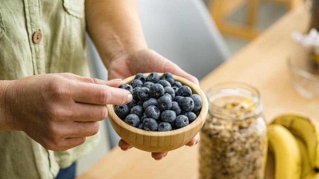 Mujer con un cuenco de arándanos en las manos.
