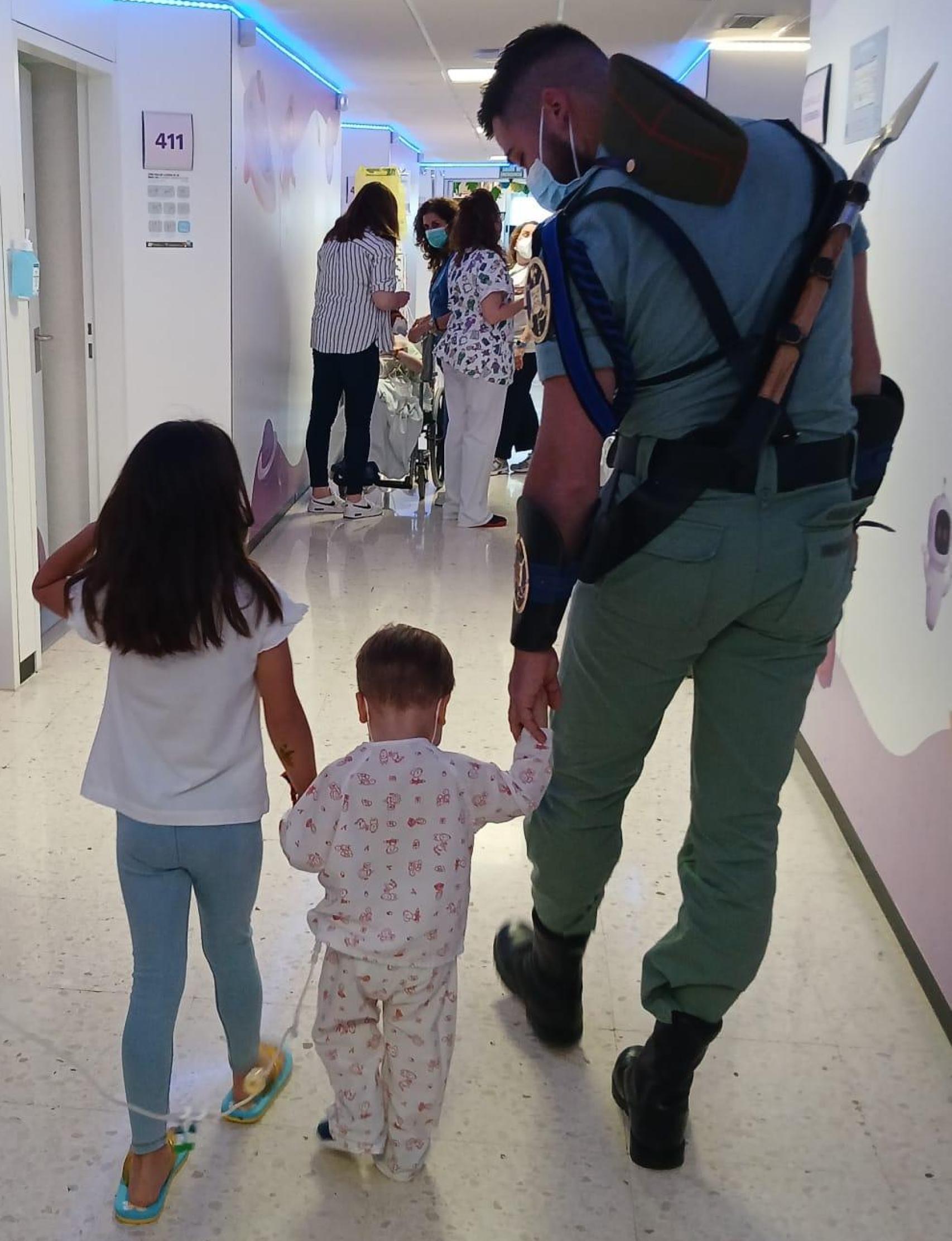 Un legionario da la mano a un niño ingresado.