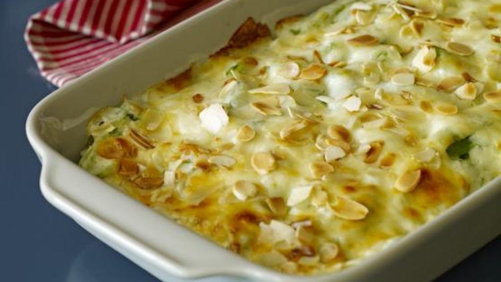 Puerros al horno, envueltos en jamón serrano y cubiertos con una capa de queso parmesano.