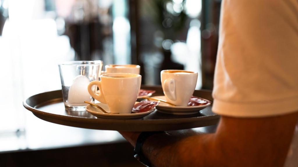 Un camarero sostiene una bandeja con cafés.