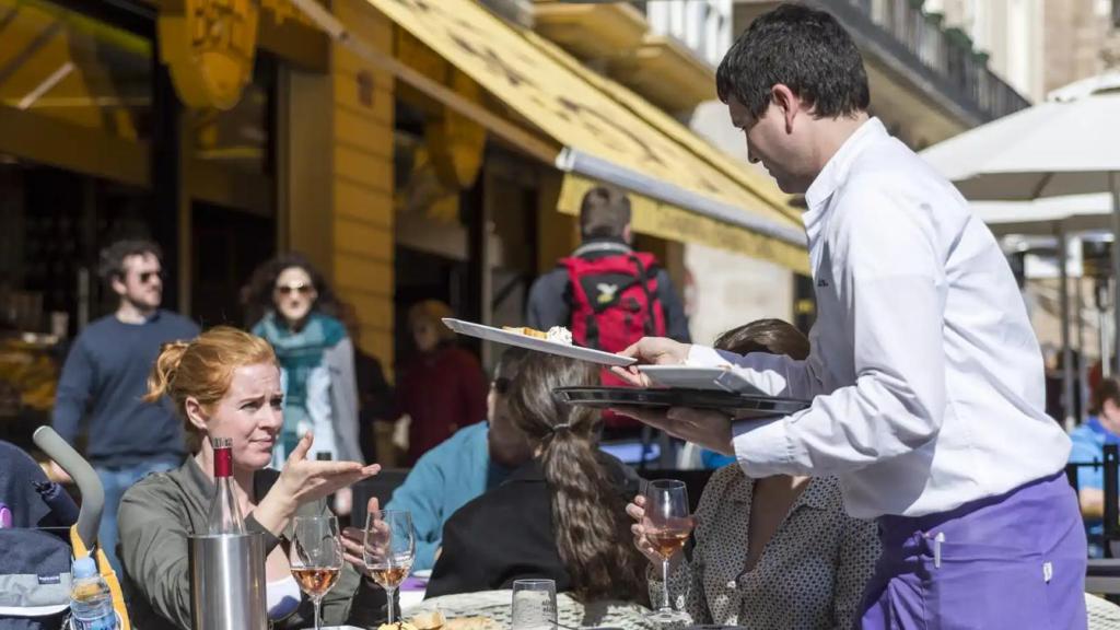 Un camarero atiende a sus clientes en una terraza.