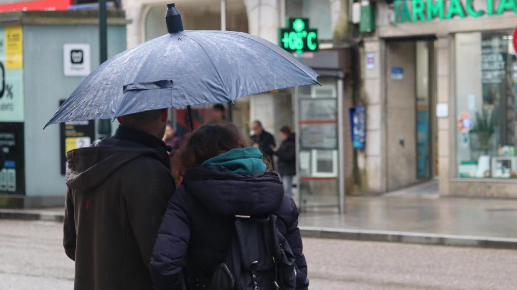 Dos turistas resguardándose de la lluvia bajo un paraguas