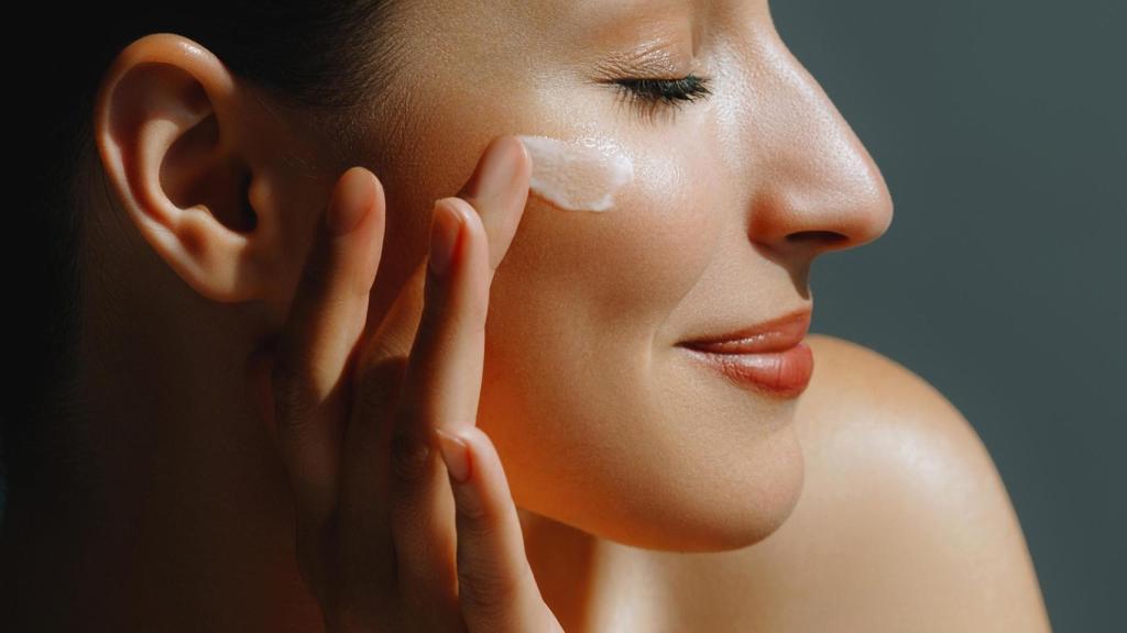 Una mujer se aplica crema hidratante en el rostro