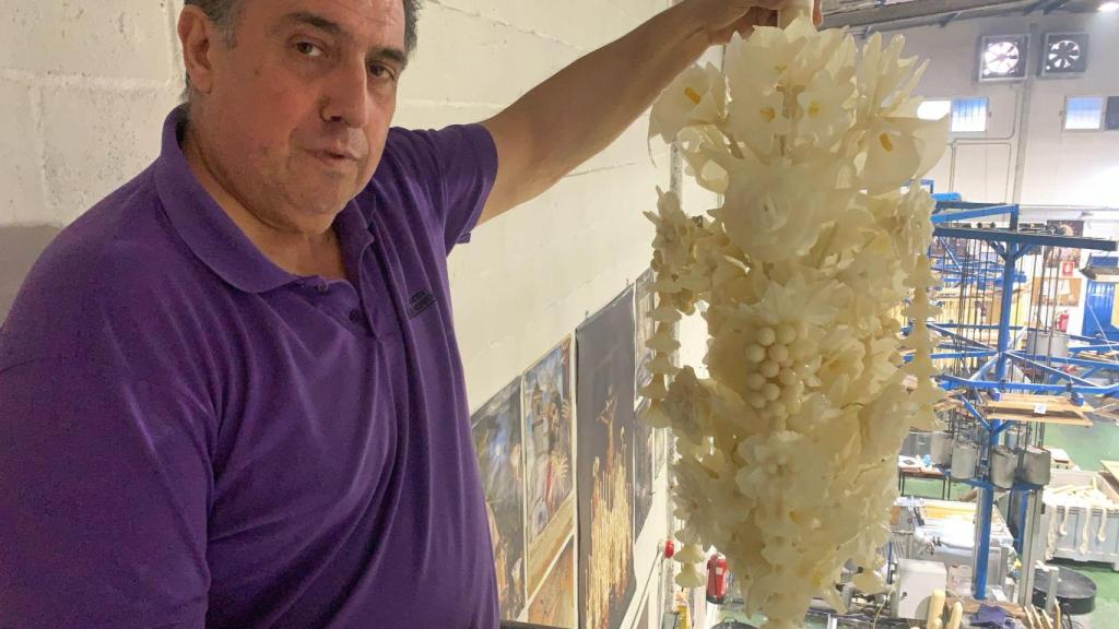 Arturo muestra uno de los adornos de flores con el detalle de unas uvas perfectamente redondas, todo de cera.