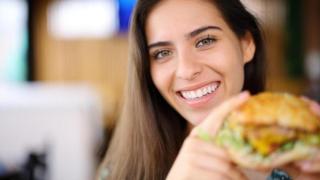Mujer sosteniendo un bocadillo.