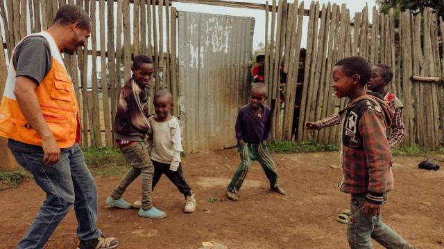 Un grupo de niños desplazados de Sudán juegan con un trabajador humanitario de World Vision.