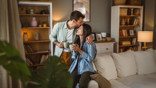Pareja sonriendo abrazada en el salón.