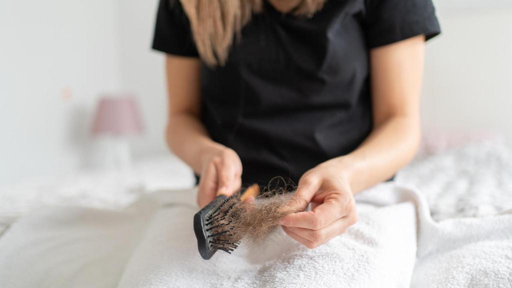 Una mujer limpiando un cepillo de pelo.