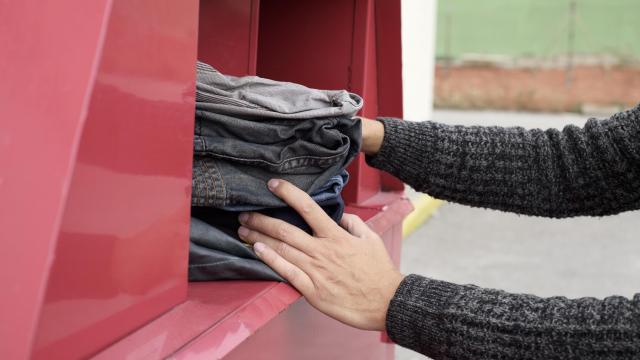 Una persona depositando ropa en un contenedor de reciclaje textil.