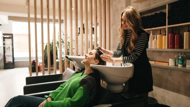 Peluquera lavándole el pelo a una clienta.