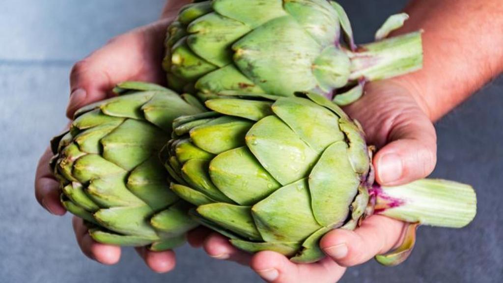 Mujer sosteniendo alcachofas entre las manos