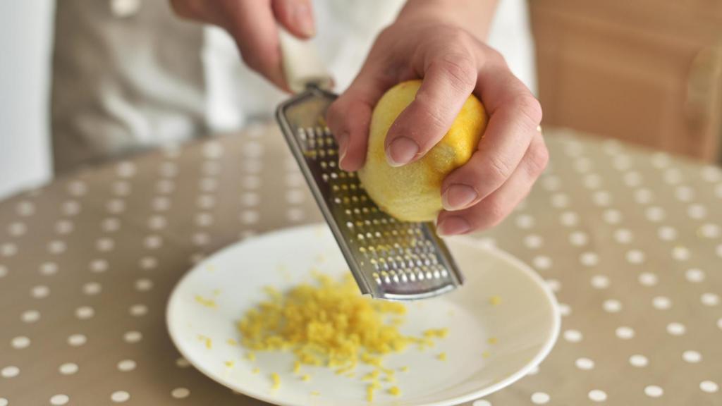 Una mano rallando un limón.