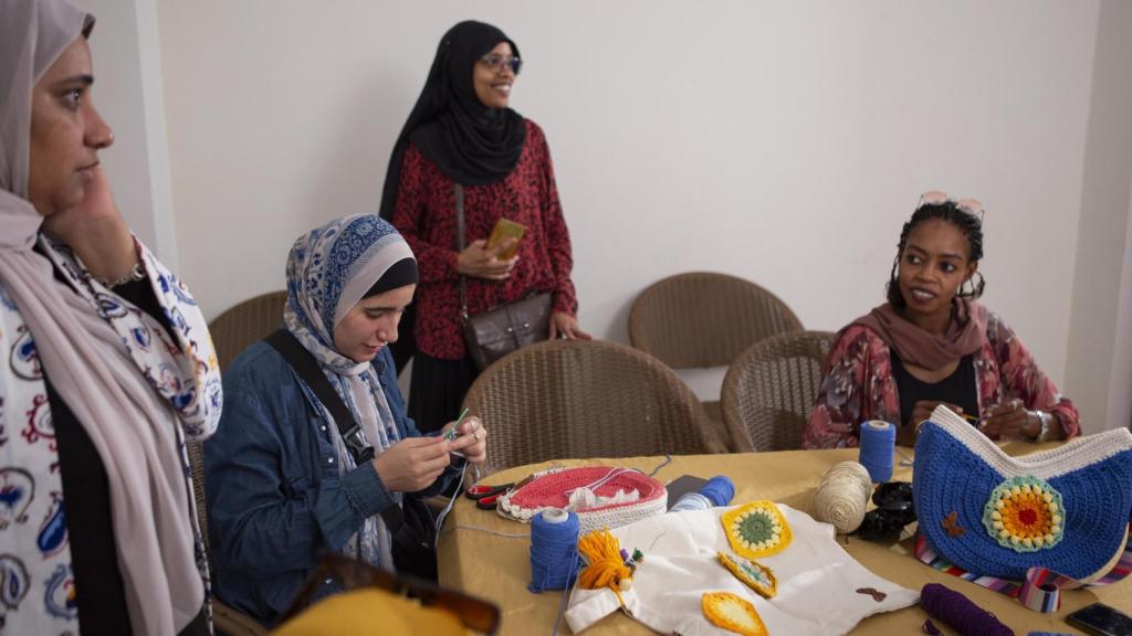 Un grupo de participantes, entre ellos los refugiados sudaneses Elham Mahmoud (derecha) y Hend Youssef (centro), asisten a una clase de crochet y costura como parte de un taller de capacitación para la subsistencia en el centro comunitario de la Iniciativa Rouh en Alejandría, Egipto.
