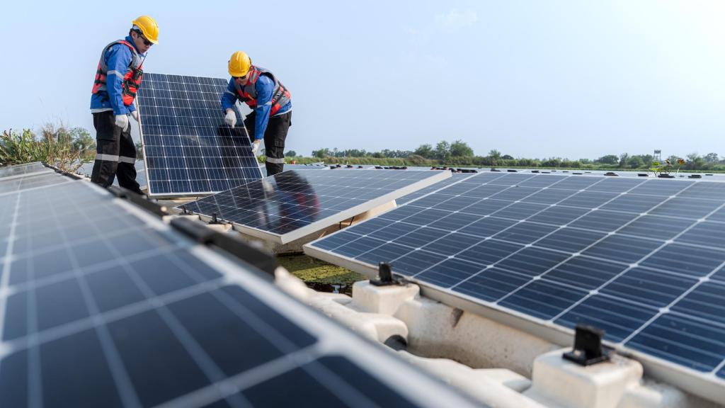 Técnicos colocando placas solares en un tejado.
