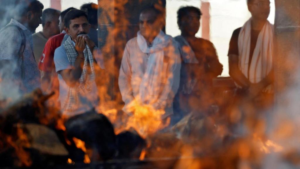 La gente reacciona junto a las piras en llamas de Yatish Parmar y su hijo Smit Parmar, que murieron en un presunto ataque militante cerca de Pahalgam en el sur de Cachemira, en un crematorio en Bhavnagar, India.