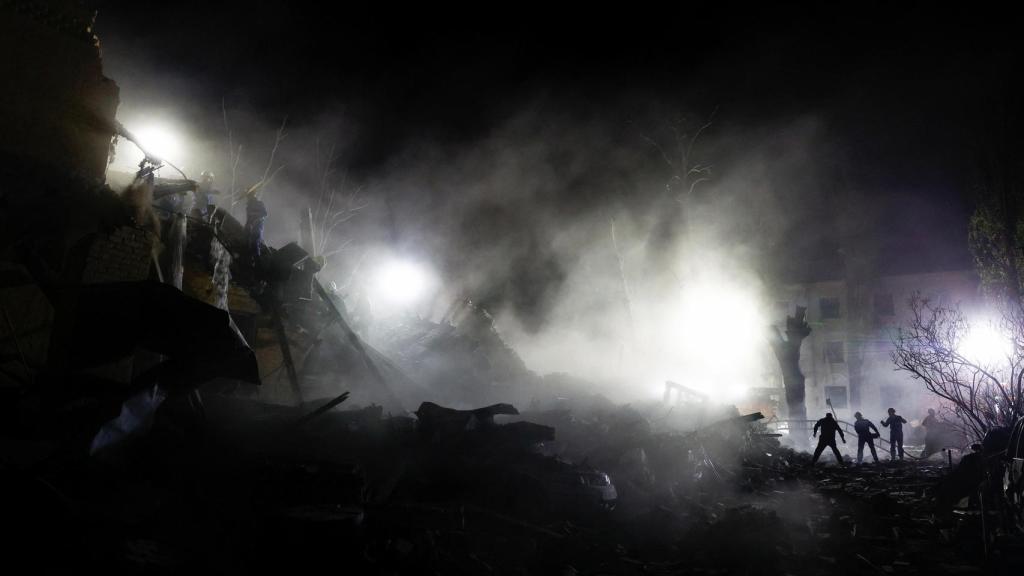 Rescatistas trabajan en el lugar de un edificio de apartamentos alcanzado por un ataque con misiles balísticos rusos en Kiev.