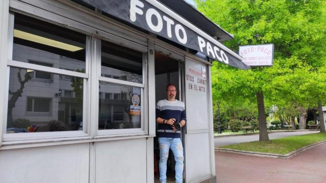 Santiago Leira, con su cámara, en el quiosco de Foto Paco en la avenida do Porto, con la comisaría del 091 reflejada en el cristal.