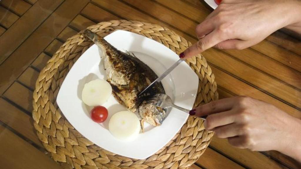 Mujer comiendo pescado.