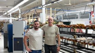 Padre e hijo posan en la fábrica de calzado en la que trabajan.